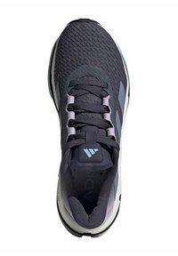 Scarpa sportiva grigio scuro con sopra texturizzato, dettagli viola e lacci piatti. Presenta una suola imbottita e un tallone sagomato per supporto.