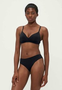 Reggiseno nero con bordi scallopati e spalline regolabili, abbinato a slip bikini a vita bassa coordinati, entrambi in un tessuto morbido ed elasticizzato.