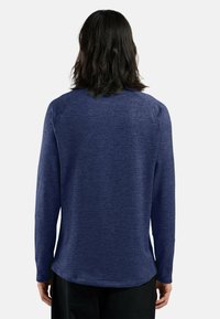 Chemise à manches longues bleu marine, tissu texturé, ourlet arrondi, manches raglan, design minimaliste sans logos ni motifs visibles.