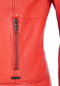 Röd läderjacka med en stilren design, dragkedjestängning och en mjuk textur med en liten loggerring vid nederkanten.