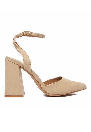 Beige Damenpumps aus Wildleder mit Blockabsatz, spitzer Zehenpartie und verstellbarem Knöchelriemen mit Schnalle vor weißem Hintergrund.