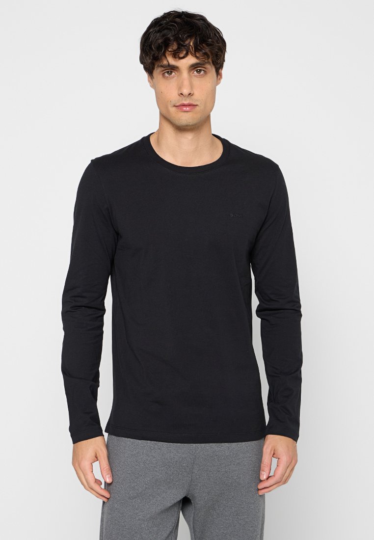 Schwarzes Langarm-T-Shirt aus weichem Stoff mit Rundhalsausschnitt und dezentem Logo auf der Brust, kombiniert mit grauen Sweatpants.