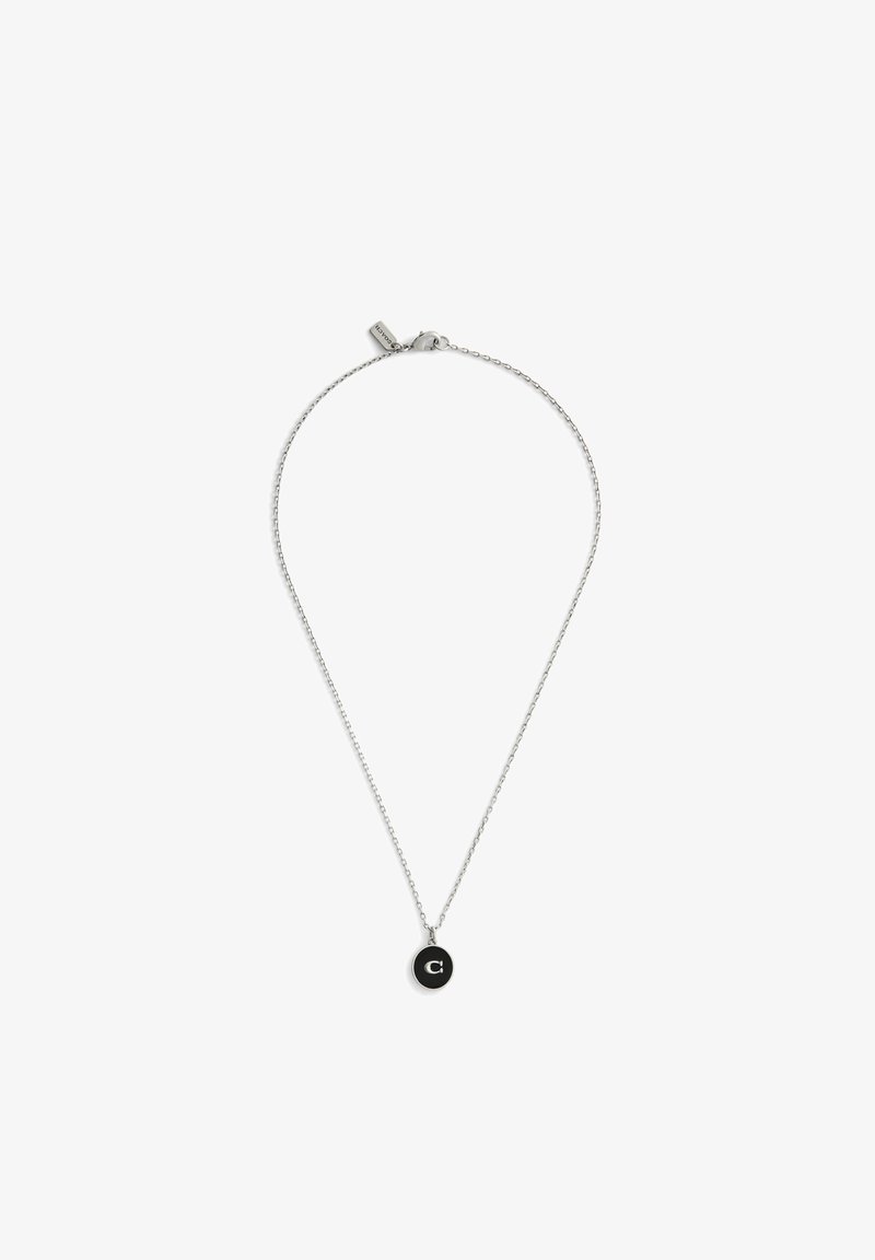 Srebrny naszyjnik z cienkim łańcuszkiem i okrągłym czarnym wisiorkiem z białą literą „C”. Łańcuszek jest cienki, z zapięciem typu karabińczyk.