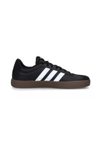 Zapatilla negra con diseño de tres rayas blancas. Textura de cuero lisa, punta redondeada y suela de goma marrón. Cierre con cordones.