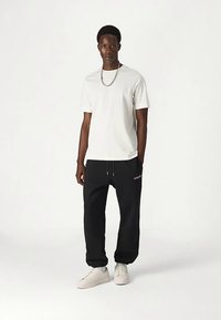 Balti trumpomis rankovėmis marškinėliai, juodos kelnės su raišteliu, balti sportbačiai ir sidabrinė grandinėlė. Paprastas dizainas, laisvas prigludimas.