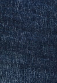 Mörkblå denimtyg med en strukturerad yta, som har små variationer i ton och ett klassiskt vävningsmönster.