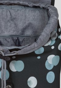 Svart tygväska med ett cirkulärt mönster i blått och ljusgrått. Inuti finns en mjuk grå foder och en justerbar dragsnörning.