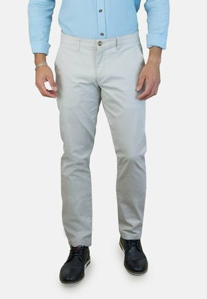 Chinos gris claro, corte recto, cierre de botón, trabillas para cinturón, bolsillos frontales; combinados con zapatos negros, textura suave, material de mezcla de algodón.