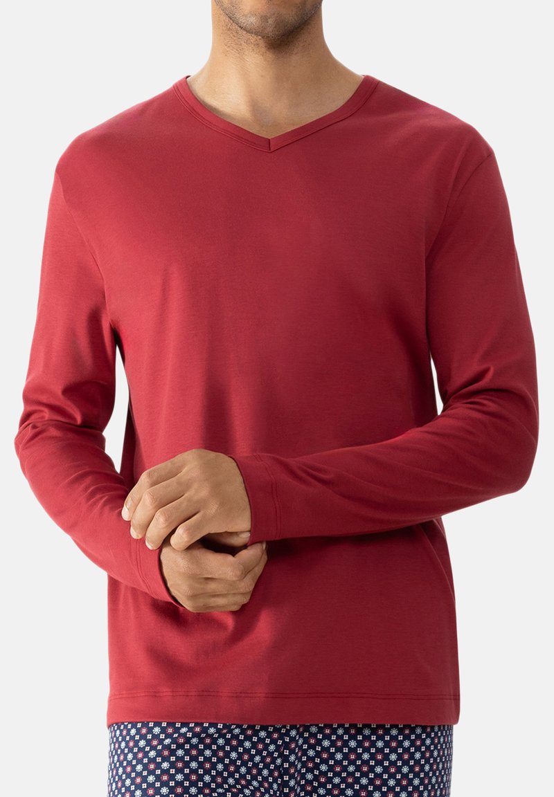 Rode langesleeve V-hals shirt gemaakt van gladde stof. De mouwen zijn aangesloten en de onderkant heeft een iets afgeronde zoom.