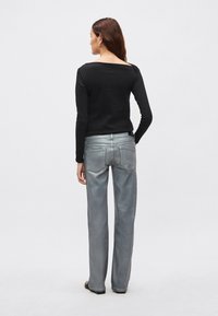 Must pikad varrukad top koos ruudukujulise kaelusega, kombineeritud helehallide, kergelt läikivate, sirgete jalgadega teksadega, millel on klassikaline viiepokiline disain.