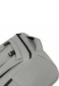 Zaino grigio con spallacci imbottiti, maniglia superiore e cerniere impermeabili nere su uno sfondo bianco semplice.