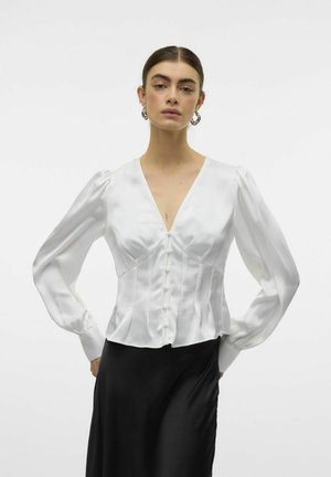 Witte satijnen blouse met een diepe V-hals, lange pofmouwen, sluiting met knopen aan de voorkant en een gestructureerde pasvorm, gedragen met een zwarte rok.