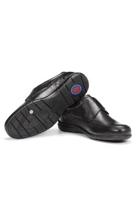 Zapatos de cuero negros con un acabado liso, que presentan una suela acolchada, un diseño sin cordones y una suela exterior de goma texturizada con un patrón de tracción.