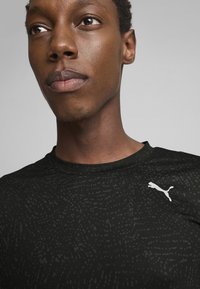 Čierne športové tričko s jemným textúrovaným vzorom, s okrúhlym výstrihom a bielym logom Puma na ľavom ramene.