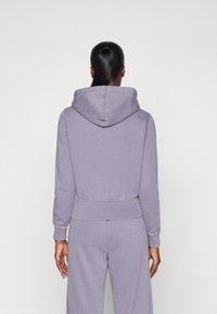 Lavender hooded sweatshirt with a cropped design, ribbed cuffs, and waistband. Soft fabric with minimal stitching detail on the back.