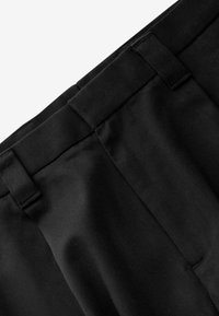 Pantalons noirs avec une texture lisse, dotés d'une taille large, de plis subtils et d'un design structuré. Aucun poquet visible ni embellissements.