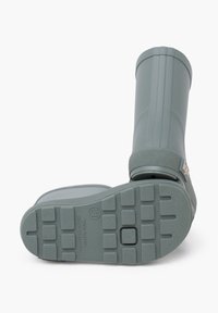 Botte de pluie en caoutchouc gris avec une semelle texturée, un dessus arrondi et un logo en relief. La vue latérale montre un design courbé et un matériau flexible.