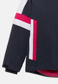 Jachetă marină cu dungi diagonale albe și roz, având o căptușeală interioară moale și închideri cu arici pe manșete. Exterior neted, impermeabil.