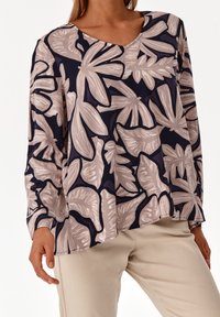 Pitkähihaisessa tummansinisessä puserossa on vaaleabeige kukkakuosi. Siinä on V-pääntie ja rento mitoitus. Valmistettu pehmeästä kankaasta, jossa on sileä pinta.