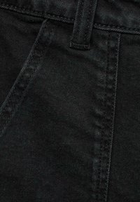 Primo piano di un tessuto denim nero che mostra dettagli di cucitura, una cucitura verticale e una cintura nella parte superiore. La texture appare liscia con lievi variazioni.