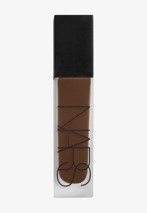 Bouteille en verre rectangulaire contenant un fond de teint liquide marron foncé avec un capuchon rectangulaire noir, logo NARS imprimé verticalement sur la bouteille.
