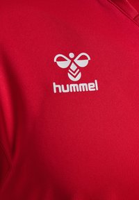 R�ød sports t-shirt lavet af glat stof, med et hvidt logo, der har et stiliseret bi-design og teksten "hummel" nedenunder.