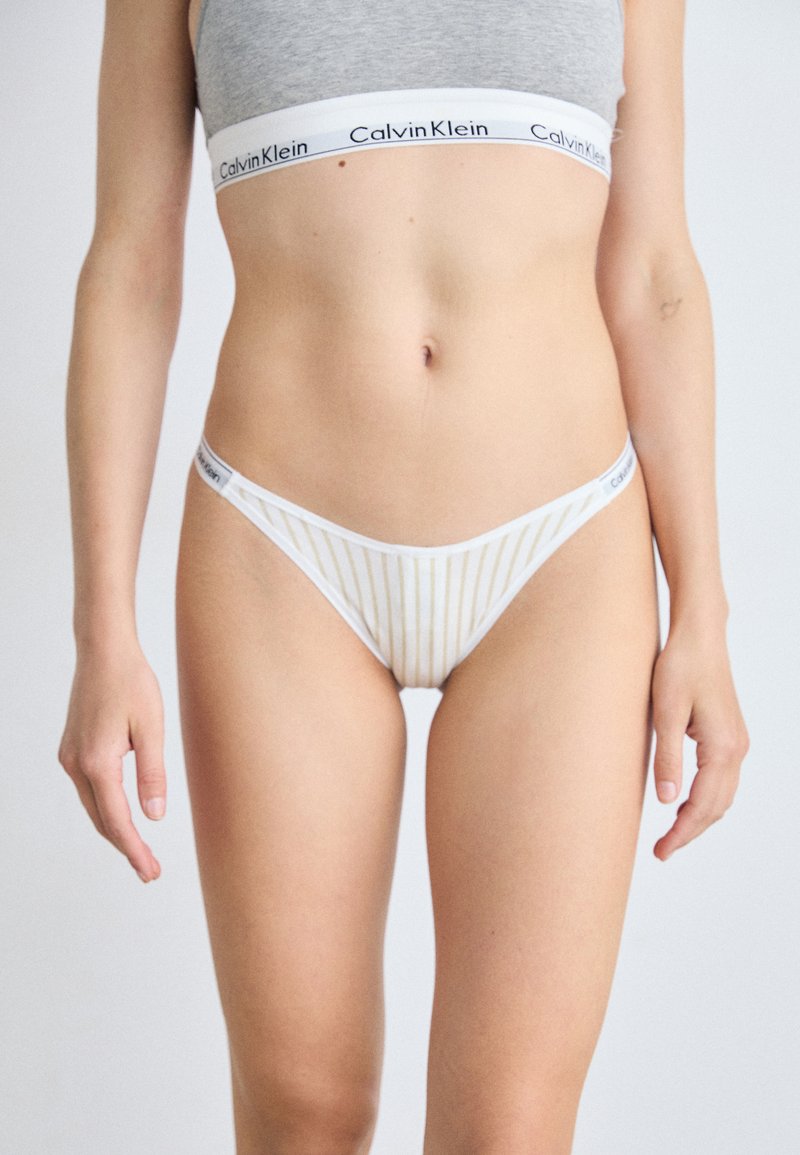 Calvin Klein witte string ondergoed heeft dunne verticale strepen en een zachte tailleband met het merkembleem. Gladde textuur; minimalistisch ontwerp.