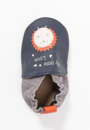 Chaussure bébé bleu marine avec cheville élastique, patch visage de lion, crinière orange et texte « Mon petit amour » avec petits cœurs blancs.