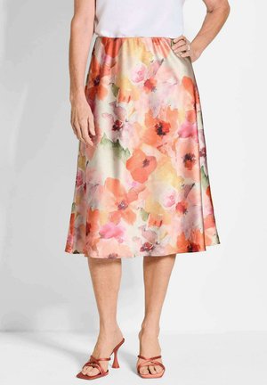 Blumiger Midirock in Rosa-, Orange- und Grüntönen, aus glattem Stoff mit einem elastischen Bund. Kombiniert mit roten, schmalen High-Heels.