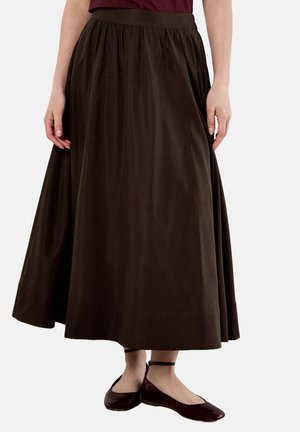 Gonna marrone a lunghezza intera con vita arricciata, realizzata in tessuto liscia. Abbinata a ballerine bordeaux, con punta quadrata e cinturino alla caviglia.