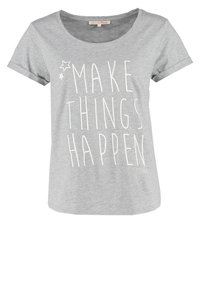 Camiseta de manga corta gris claro con el texto blanco "HAZ QUE LAS COSAS SUCEDAN" y dos pequeños gráficos de estrellas cerca del escote.