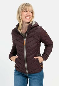 Bordeauxfarbene Puffjacke mit Kapuze, mit einem Chevron-Steppdesign, frontaler Reißverschluss und braunen Lederelementen. Getragen mit blauen Jeans.