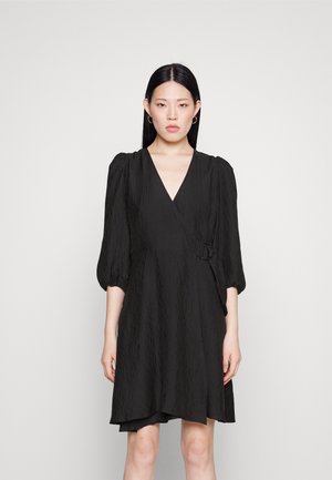 Μαύρο φόρεμα περιτυλίγματος με υφή, κοντά φουσκωτά μανίκια, V-λαιμόκοψη και διακοσμητική αγκράφα στο πλάι. Λείο και ελαφρώς ρέον σχέδιο.