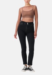 Top trasparente marrone a maniche lunghe con scollatura quadrata abbinato a jeans neri a vita alta, completando il look con sneakers nere.