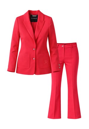 Completo donna su misura rosso con blazer aderente caratterizzato da due bottoni argento, tasche frontali e pantaloni svasati abbinati con chiusura a bottone argento.