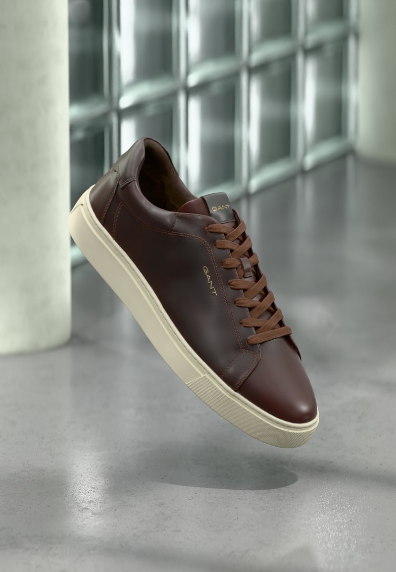 Adidași din piele maro cu vârf rotunjit, șireturi maro și talpă din cauciuc bej. Prezintă o branduire minimă pe lateral.