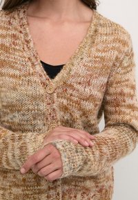 Pletený kardigan s výstřihem do V, v hnědých a béžových tónech, s třemi dřevěnými knoflíky a žebrovanými manžetami. Texturovaný, teplý materiál z vlněné směsi.
