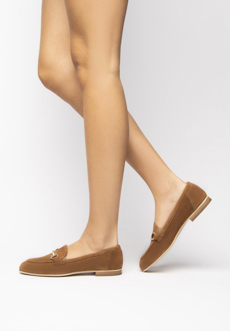 Brown suede loafers with a rounded toe, gold accent hardware on the upper, and a low, beige rubber sole. Smooth texture throughout.