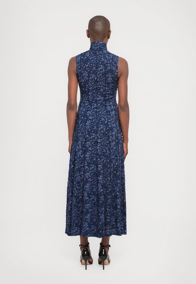 Rochie fără mâneci, cu imprimeu floral bleumarin, guler înalt, corset ajustat și fustă pliată fluidă, asortată cu pantofi cu toc înalt negri.