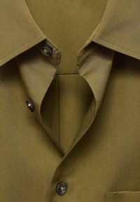 Olive green collared shirt featuring a smooth fabric texture, two black buttons, and a placket with an angled cut.