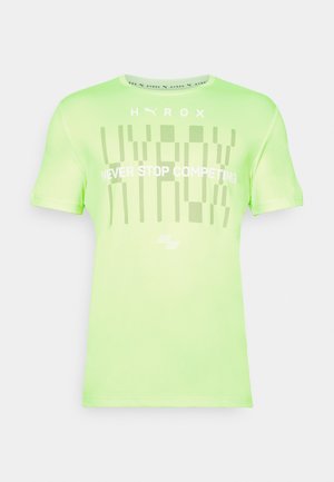 Zaļa sporta T-kreklu ar īsām piedurknēm, tajā ir grafiska apdruka, kas ietver "HYROX" un "NEVER STOP COMPETING" baltā krāsā. Gluda tekstūra.