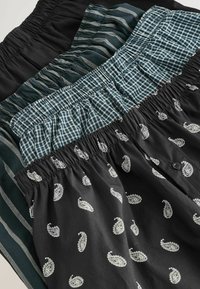 Drei Shorts: schwarz mit weißem Paisleydruck, grün karriert und gestreift. Weicher Stoff und elastische Taillenbündchen.