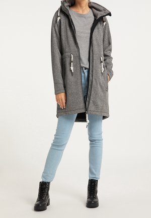 Grå långärmad hujacka med dragkedja, utrustad med dragsko och sidofickor. Matchas med ljusblå jeans och svarta stövlar.