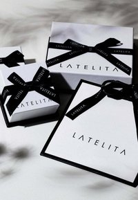 Three gift boxes in white, featuring black ribbon and the brand name "LATELITA" in bold lettering, with a clean design and elegant structure.