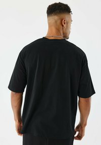 Camiseta de algodón negra con un corte relajado y mangas cortas, que muestra una textura suave y un diseño simple. Sin gráficos ni patrones visibles.