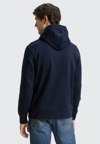 Marineblauer Kapuzenpullover mit großer, gefütterter Kapuze, gerippten Bündchen und Saum. Hergestellt aus weichem Stoff, zeichnet sich durch ein schlichtes Design ohne sichtbare Logos aus.