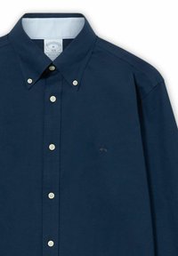 Camicia blu navy con bottoni bianchi, punte del colletto abbottonate e logo ricamato sottile sul petto.