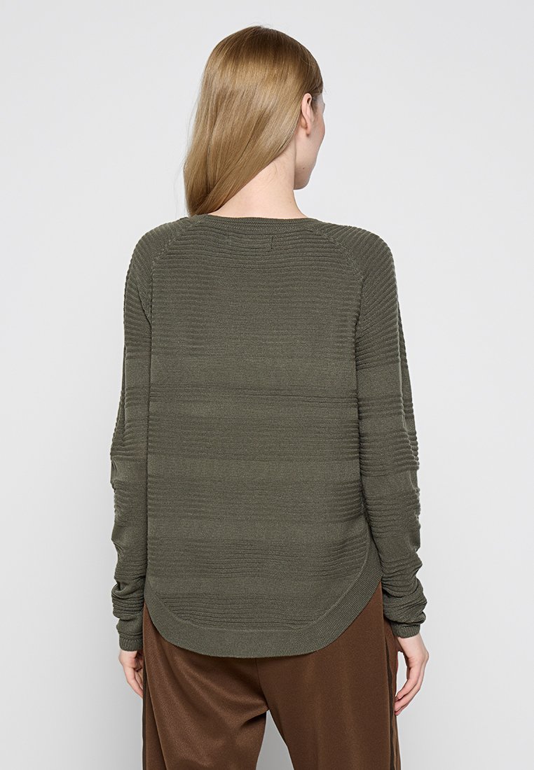 Maglione lungo a maniche lunghe verde oliva con coste orizzontali e orlo arrotondato. Realizzato in tessuto a maglia texturizzata. Vestibilità rilassata.