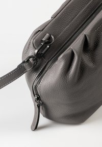 Gray leather crossbody bag with a textured finish, featuring a top zipper, leather strap, and metal hardware with a matte black accent.