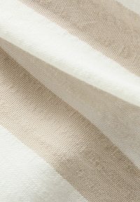Tissu textile présentant des rayures diagonales en beige doux et blanc crème, avec une surface texturée et un motif tissé.